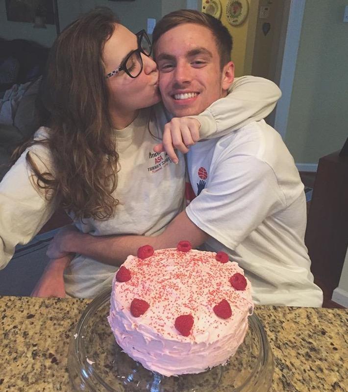 Senior Ian Sekol hugs his significant other behind a special Valentines Day themed cake.