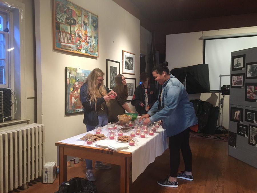 Seniors Colleen Cragun and Arleena Allen prepare a table full of goodies for visitors at the artwork showing on Main Street. The creations from multiple students were displayed on the walls.