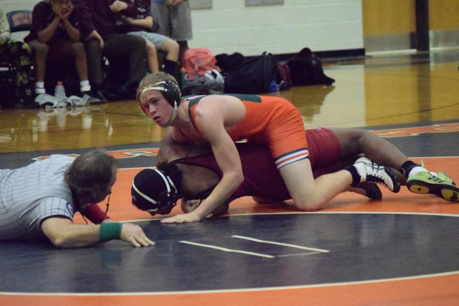 Pinning his opponent to the ground, senior Casen Chumley attempts to win his
match.