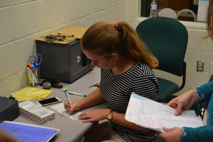 Writing a receipt for a deposit, junior Stephanie Scheffer diligently works her shift in the newly opened Cougar Branch.