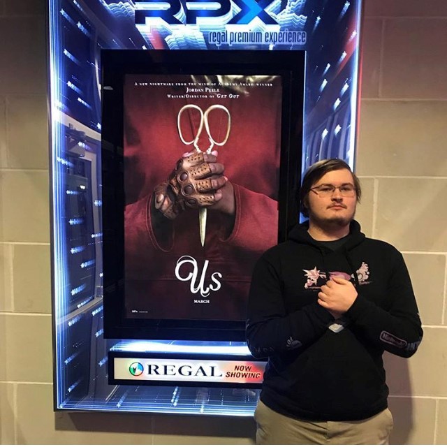 Posing in front of the movie poster, Senior Connor Roy prepares to see the new horror movie, Us.